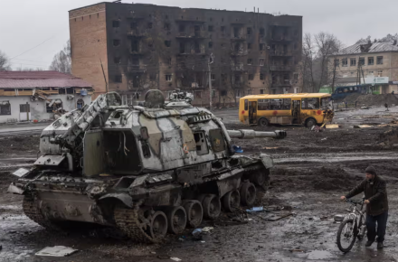 A man pushes his bike through mud and debris past a destroyed Russian self-propelled gun in front of the central train station in Trostianets, Ukraine, in March. Photograph: Chris McGrath/Getty Images