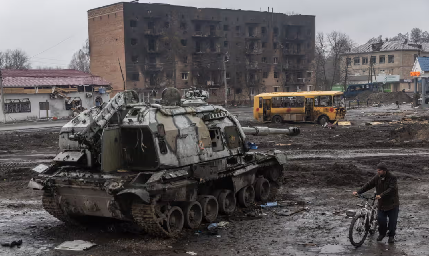 A man pushes his bike through mud and debris past a destroyed Russian self-propelled gun in front of the central train station in Trostianets, Ukraine, in March. Photograph: Chris McGrath/Getty Images